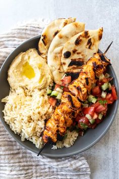 a plate with chicken, rice and pita bread on it next to a fork