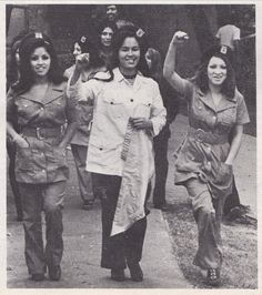 an old black and white photo of women dressed in uniforms walking down the street together