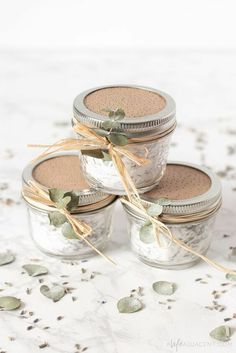 four mason jars filled with hot chocolate and sprinkled with leaves on a table