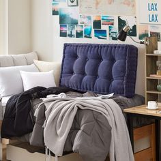 an unmade bed with blankets and pillows on it in front of a book shelf