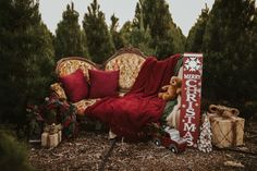 a couch covered in red blankets and christmas decorations next to a pile of presents on the ground