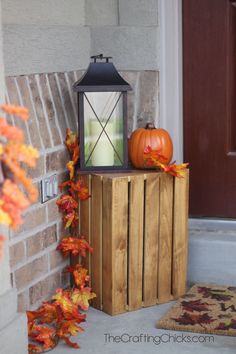 the front door is decorated with fall leaves and an old fashioned lantern on it's stand