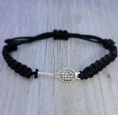 a black cord bracelet with a silver tennis racket charm