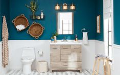 a bathroom with blue walls and white tile flooring, two wicker baskets hanging on the wall