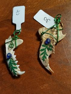 two pieces of animal bone with green and blue decorations on them sitting on a table