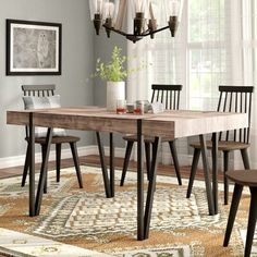 a dining room table with four chairs and a chandelier hanging from the ceiling