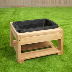 a wooden bench with a black planter on it's side in the grass