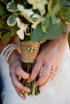 the bride is holding her bouquet with green and white flowers in it's hands