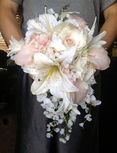 a person holding a bouquet of white and pink flowers in front of their face,