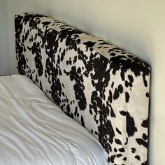 a cow print upholstered headboard on a bed with white sheets and pillows