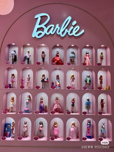 barbie dolls are displayed on shelves in a display case with the word barbie above them