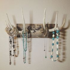 the antlers are hanging on the wall with beaded necklaces and bracelets