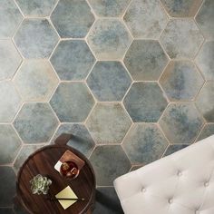 a white chair and table in front of a wall with hexagonal tiles on it