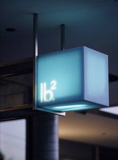 an illuminated sign hanging from the ceiling in front of a building with glass blocks on it