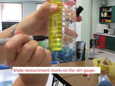 a person holding up a plastic container filled with colored rocks and sand in a classroom