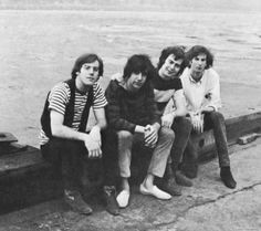 four young men sitting next to each other near the water