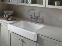 a white kitchen sink sitting on top of a counter next to cupboards and cabinets