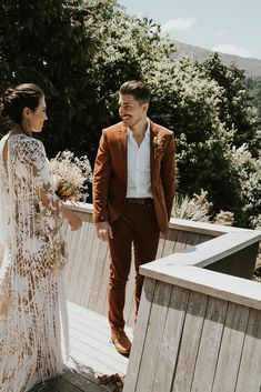 a bride and groom standing on a deck holding hands