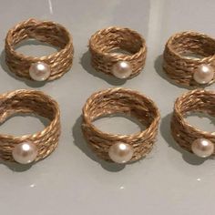 four rings with pearls are sitting on a white surface and one is made out of rope