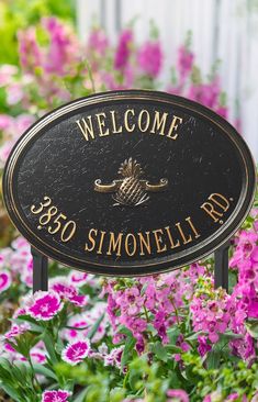 a welcome sign is in front of some pink and purple flowers with the words, welcome 350 simonellelli rd on it