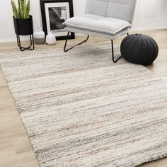 a living room area with a rug, chair and potted plant