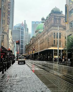 a wet city street with buildings in the background