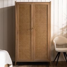 an armoire with wicker doors next to a white chair