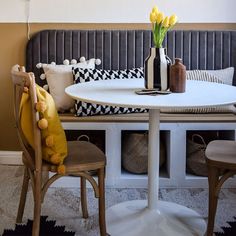 a white table with two chairs and a vase on top of it next to a bench