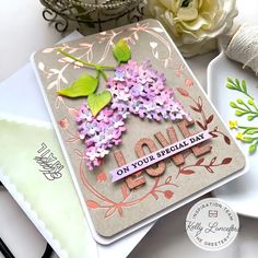 a close up of a card on a table with flowers and other items in the background