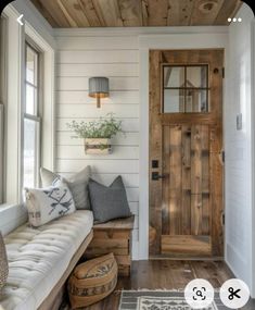 a living room with a couch and wooden door in the corner, next to a window