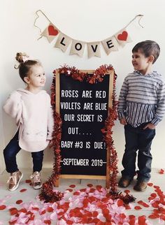 two young children standing next to a sign that says roses are red violets are blue our secret is out