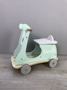 a green wooden toy scooter with the word noah on it's side