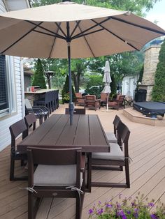 an outdoor table and chairs with umbrellas on the deck