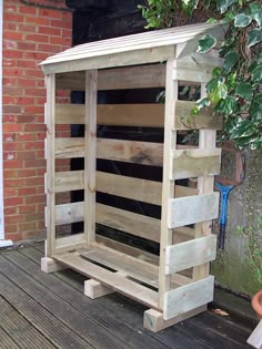 a wooden bench made out of pallets on a deck next to a brick wall