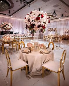 a table set up for a formal function with white linens, gold chairs and floral centerpieces