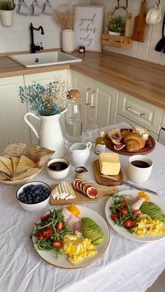 a white table topped with plates of food and cups of coffee on top of it