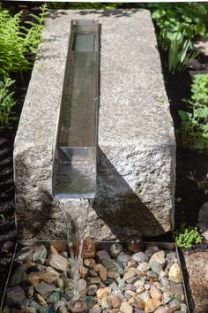 a water fountain with rocks and plants around it