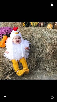 a baby dressed in chicken costume laying on hay