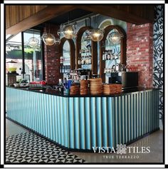 a blue metal bar with lights hanging from it's ceiling and some plates on the counter