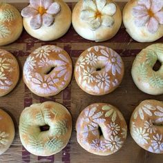 twelve donuts with frosting and flowers on them sitting on a table next to each other