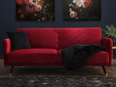 a red couch sitting in front of two paintings