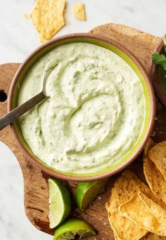 guacamole dip in a bowl surrounded by tortilla chips and limes