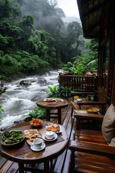 a table with food on it next to a river and some trees in the background