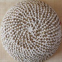 a large round woven cushion sitting on top of a white table cloth covered flooring