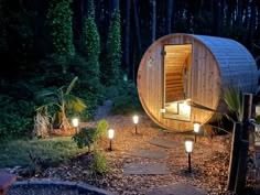 an outdoor sauna is lit up at night in the woods with candles around it