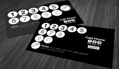 two business cards with numbers on them sitting on a wooden table in black and white