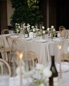 the table is set with white flowers, candles and wine bottles for an elegant wedding reception