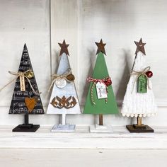 three small christmas trees are sitting on the mantle with ribbons and tags attached to them