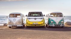 three vw buses parked next to each other near the ocean