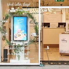 a store front window with the words wedding shop written on it's glass and surrounded by greenery